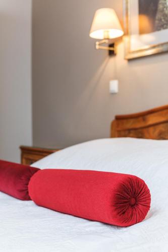 a red pillow sitting on top of a bed at Hotel Czarna Róża in Toruń