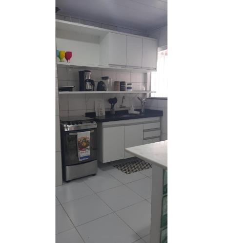 a kitchen with white cabinets and a stove top oven at Casa com piscina em Carapibus - Jacumã in Conde