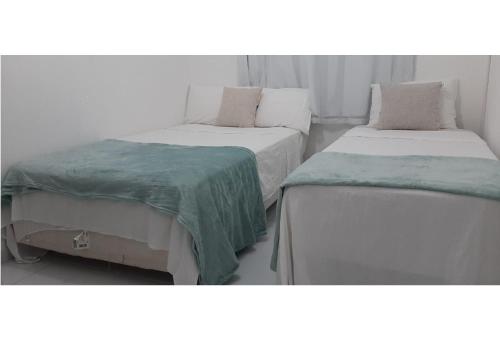 duas camas com lençóis verdes num quarto em Casa com piscina em Carapibus - Jacumã em Conde