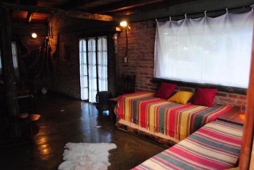 a room with two beds and a brick wall at CABAÑAS LA ARBOLEDA DE TOMASA in Villa Rumipal