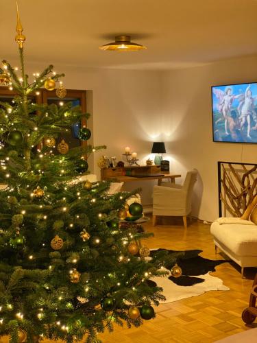 a green christmas tree in a living room at Charmantes Garten-Apartment: Erholung im Chiemgau in Unterwössen