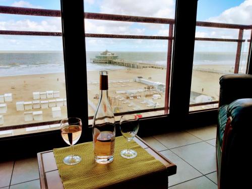 Beachview Pier Blankenberge في بلانكنبرخ: كأسين من النبيذ على طاولة مطلة على الشاطئ