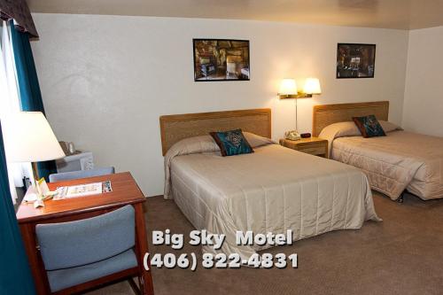 Habitación de hotel con 2 camas y escritorio en Big Sky Motel, en Superior