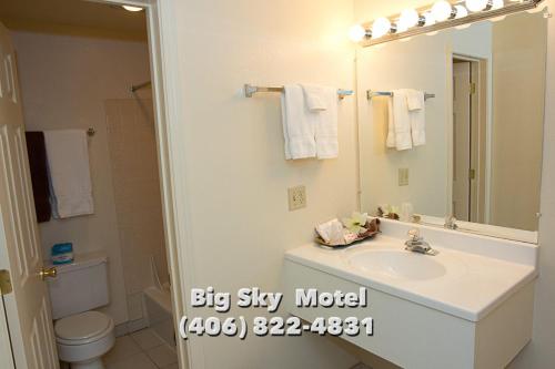 a bathroom with a sink and a toilet and a mirror at Big Sky Motel in Superior