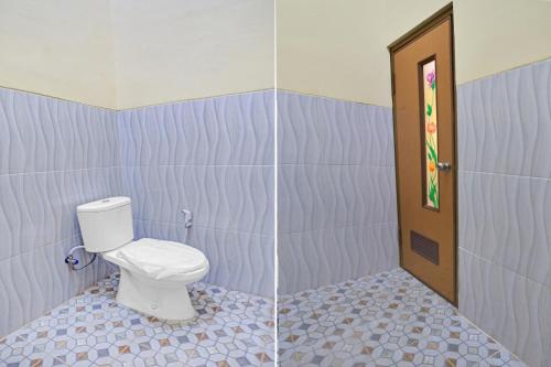 a bathroom with a toilet and a door at OYO 90737 Losmen Aini Syariah in Batu