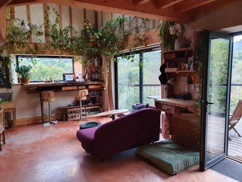 un salon avec un canapé violet et des plantes dans l'établissement Maison atypique et chaleureuse dans la nature, à Arras-en-Lavedan