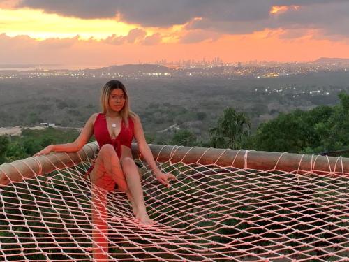 a woman sitting on top of a net at sunset at ADA MARINA - 3 acomodaciones con jacuzzi, malla y vista a Cartagena, 1 acomodacion con jacuzzi escondido, zona social con piscina infinita in Turbaco