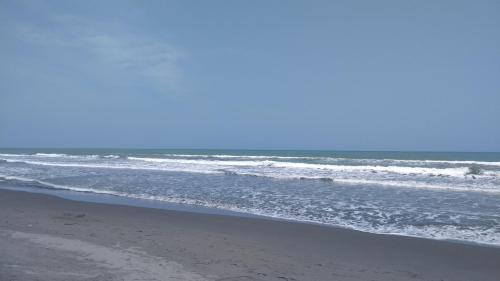an empty beach with waves in the ocean at Zéfiro Hostal in San Bernardo del Viento
