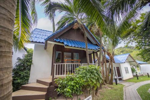 a house with a blue roof and palm trees at Assava Dive Resort - SHA Plus in Koh Tao