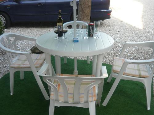 a white table with two chairs and a bottle of wine at Szent István Panzió in Hódmezővásárhely