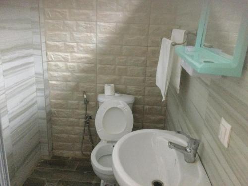 een badkamer met een wit toilet en een wastafel bij Warang - Nianing Chambres,Salle de séminaires et réunion in Darou Rhamane