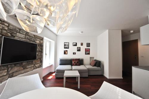 a living room with a couch and a tv on a stone wall at Historic center shelter in Piran
