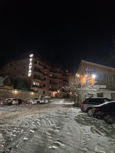 a parking lot with cars parked in the snow at night at Taulu in Dombay