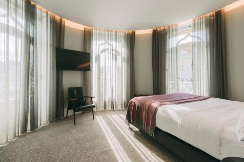 a bedroom with a large bed and a large window at 1908 Lisboa Hotel in Lisbon