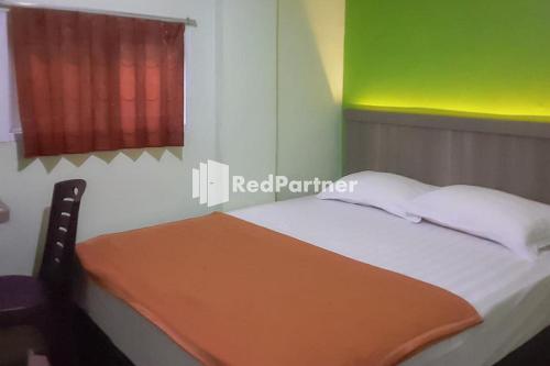 a bedroom with a bed with a red window at Guest House Anak Raja Pangkalan Bun Syariah Mitra RedDoorz in Pangkalan Bun