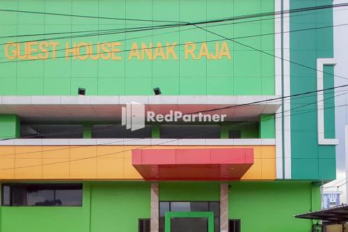 a colorful building with a sign on the side of it at Guest House Anak Raja Pangkalan Bun Syariah Mitra RedDoorz in Pangkalan Bun