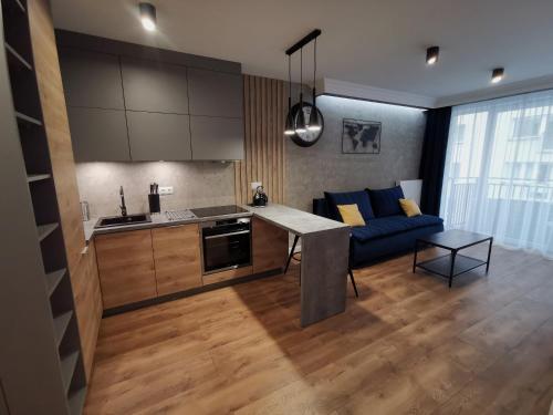 a kitchen and a living room with a blue couch at Apartament nad Odrą APARTMENT RIVER HOUSE in Szczecin