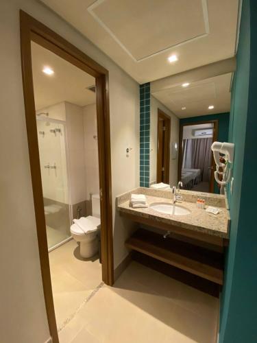 a bathroom with a sink and a toilet and a mirror at Apartamento no Solar das Águas Resort em Olímpia - SP in Olímpia