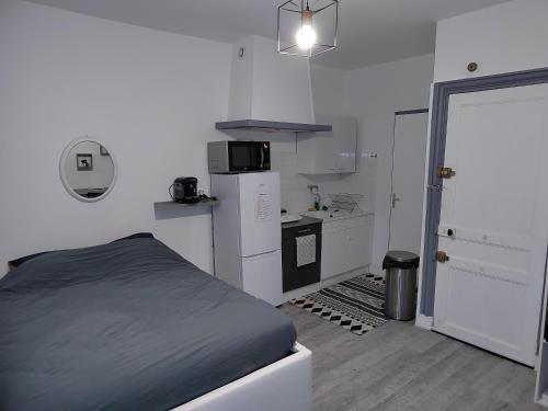 een slaapkamer met een bed, een koelkast en een keuken bij Studio Le Nougat in Montélimar