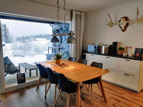 cocina con mesa de madera, sillas y ventana en Book in Borgafjäll - New cabins for rent at the slalom slope, en Borgafjäll