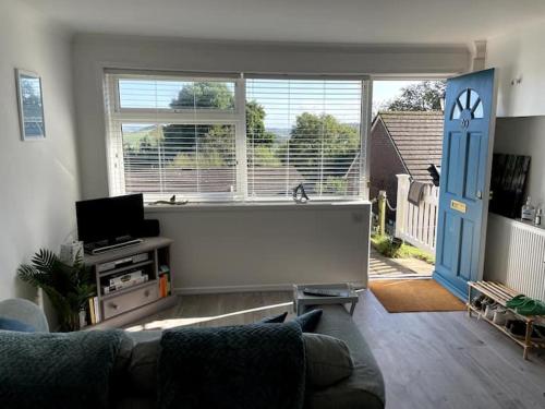 a living room with a couch and a large window at Self-catering studio in beautiful Charmouth in Charmouth