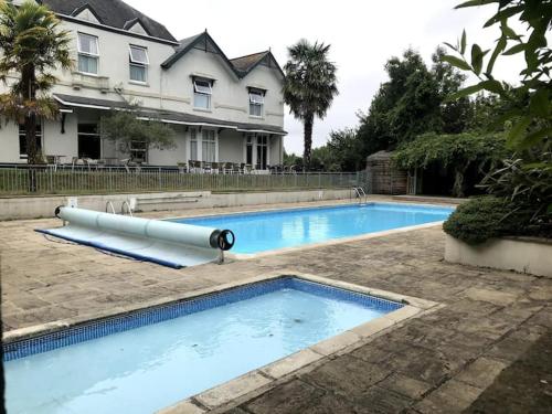 a large swimming pool in front of a house at Self-catering studio in beautiful Charmouth in Charmouth