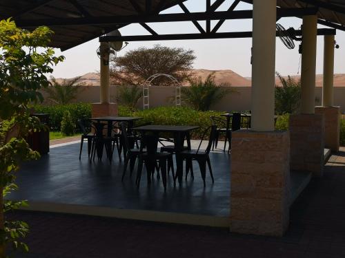 a patio with tables and chairs under a roof at Almorouj Farm inn - Bidiya in Bidiyah