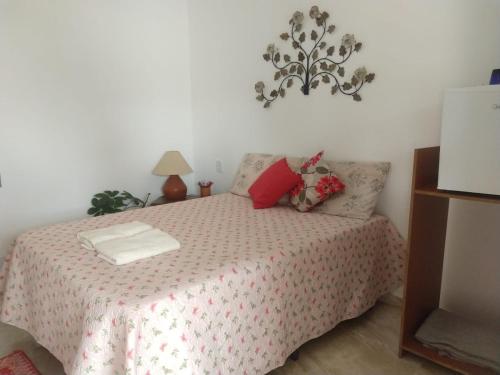 Schlafzimmer mit einem Bett mit rosa Tagesdecke in der Unterkunft Suítes Ninho da Águia Saquarema in Saquarema