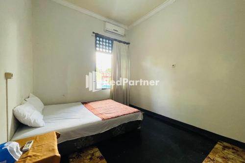 a small bedroom with a bed and a window at Langko 48 RedPartner in Tanjungkarang