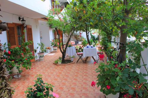 a patio with a table and some trees and flowers at Vaya Zorba Studios in Skiathos Town