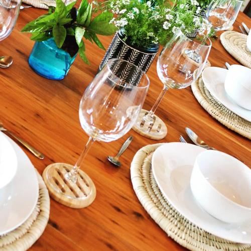 a wooden table with wine glasses and plates on it at Pura Vida Tofo Beach Houses in Praia do Tofo