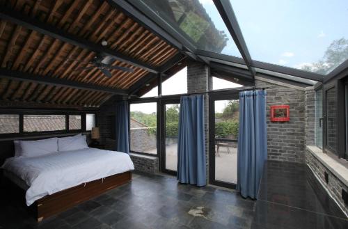 a bedroom with a bed and large windows at Brickyard Retreat at Mutianyu Great Wall Adjoin to Mutianyu Great Wall - Room with the View of Great Wall - Chinese massage experience - Vehicle Shuttle Service - International Catering - SPA& Nail Beauty Facilities in Huairou