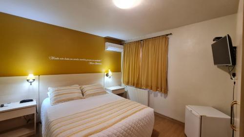 a hotel room with a bed and a television at Pousada Pinhão e Poesia in Canela
