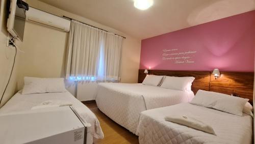 a hotel room with two beds and a purple wall at Pousada Pinhão e Poesia in Canela