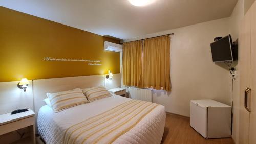 Habitación de hotel con cama y TV en Pousada Pinhão e Poesia, en Canela