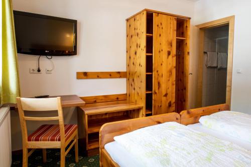 a bedroom with a desk and a bed and a tv at Gasthof Dreiländereck in Schwarzenberg am Bohmerwald
