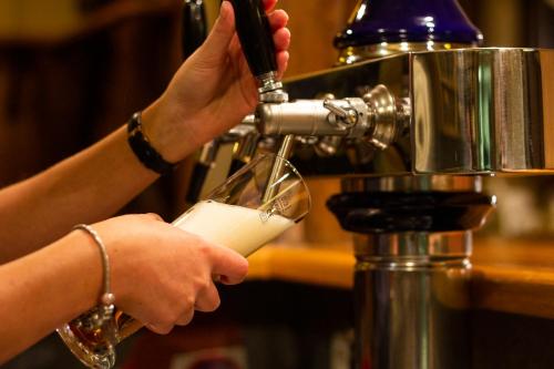 a person is pouring a drink into a glass at Gasthof Dreiländereck in Schwarzenberg am Bohmerwald