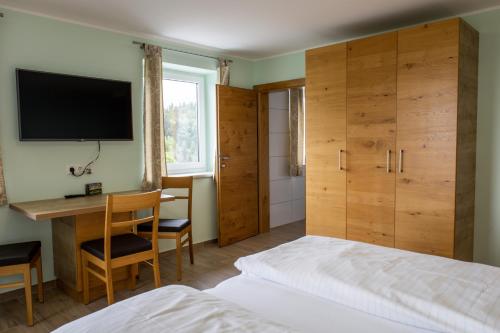 a bedroom with a bed and a desk and a television at Gasthof Dreiländereck in Schwarzenberg am Bohmerwald