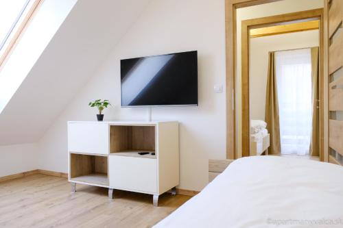 a white bedroom with a tv on a wall at Apartmány Valča in Valča