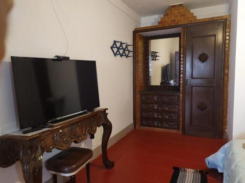 uma sala de estar com uma televisão e uma mesa de madeira em Pousada Casa Direita em Tiradentes