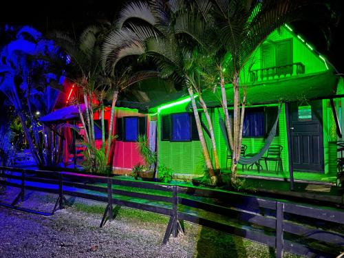 a green house with palm trees in front of a bench at Alemao Cabanas in Camburi
