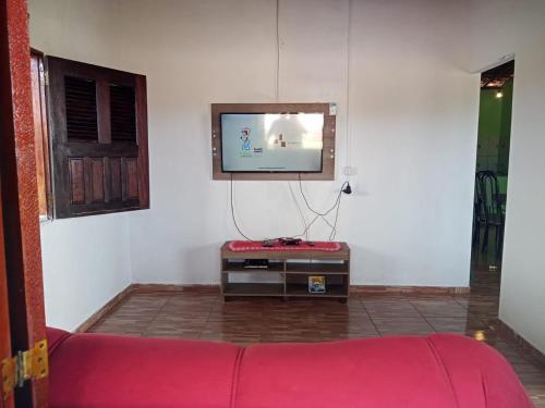 ein Wohnzimmer mit einem roten Sofa und einem Flachbildfernseher in der Unterkunft Casa Gael (Gisele & Lucimar) in Atins