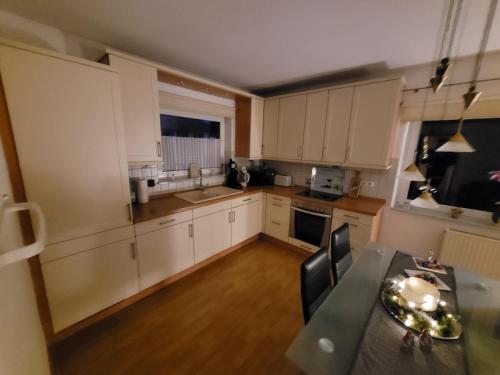 a small kitchen with white cabinets and a table at Ferienwohnung mit Terrasse für bis zu 4 Personen in Balve
