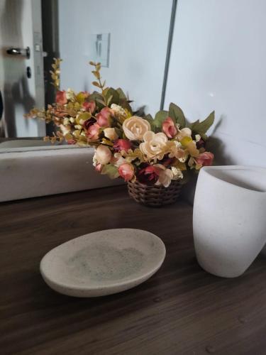 a basket of flowers next to a plate and a vase at Apto Duplex com Mezanino in Juquei