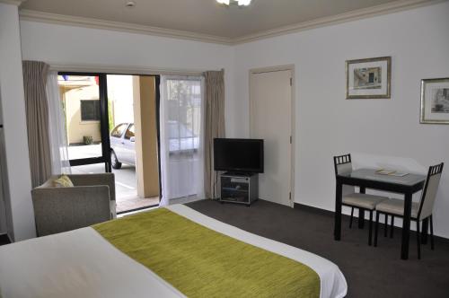 a bedroom with a bed and a table and a television at Tuscany Villas Whakatane in Whakatane