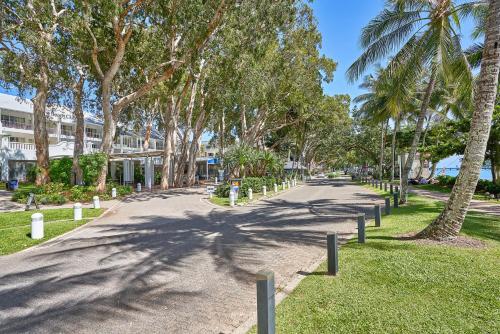 a street with palm trees on the side of a road at Oceanfront Penthouse Apartment Beach Club Palm Cove in Palm Cove