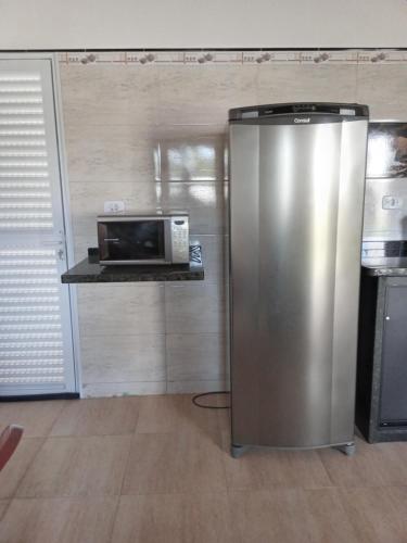 a stainless steel refrigerator in a kitchen with a microwave at Casa de Praia da Ju - Caraguatatuba in Caraguatatuba