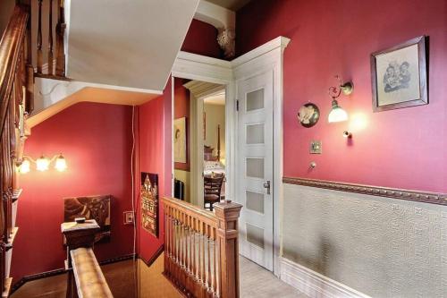 un couloir aux murs rouges et un escalier dans l'établissement 1888 Victorian House Old Quebec City, à Québec