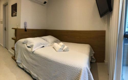 een kleine slaapkamer met een bed met witte lakens bij Brooklin Studios I Em frente ao metrô Brooklin in Sao Paulo