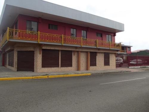 un edificio rosso con balcone su una strada di Hotel Costa del Sol a Puerto Limón